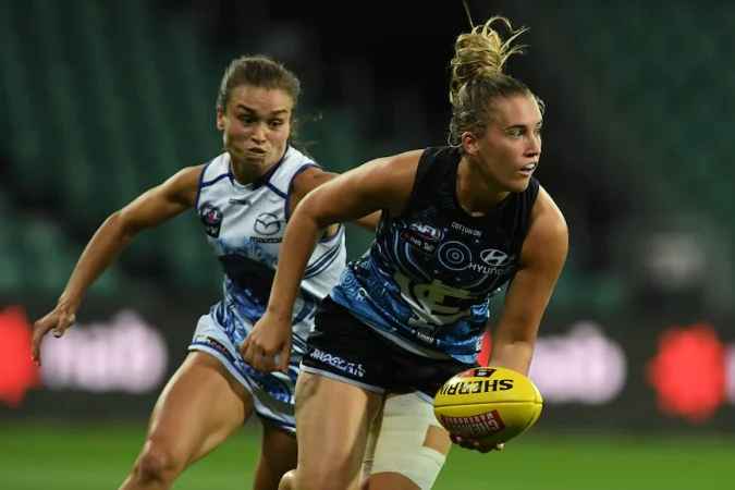 A Carlton AFLW player runs with the ball.