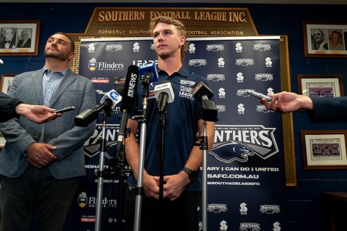 Jason Horne-Francis berdiri di belakang mikrofon di South Adelaide Football Club