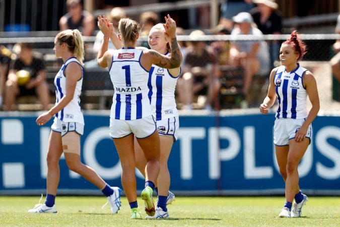 North Melbourne AFLW players high-five to celebrate a goal against Richmond.