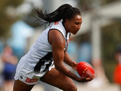 A Collingwood AFLW player runs with the ball against the Western Bulldogs.
