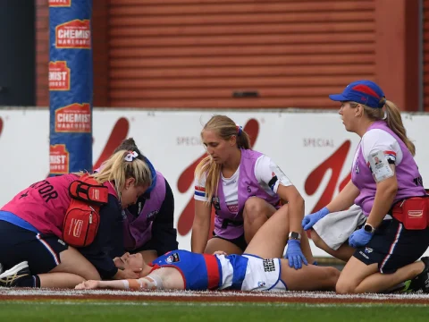 Bulldogs AFLW player Kirsten McLeod is attended to by a doctor and physios as she lies on the ground