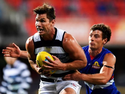 A Geelong Cats AFL player marks the ball with both hands in front of his stomach.