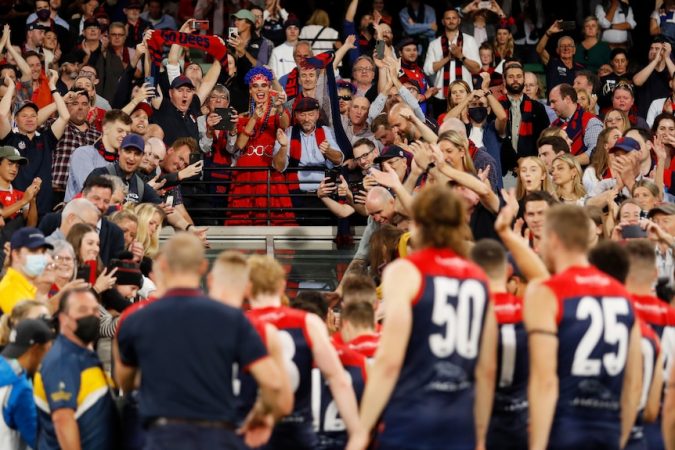 Melbourne fans hang over the race to applaud Melbourne players as they leave the field