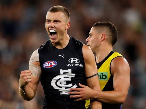 Patrick Cripps pumps his fist in celebration in the vicinity of a Richmond player
