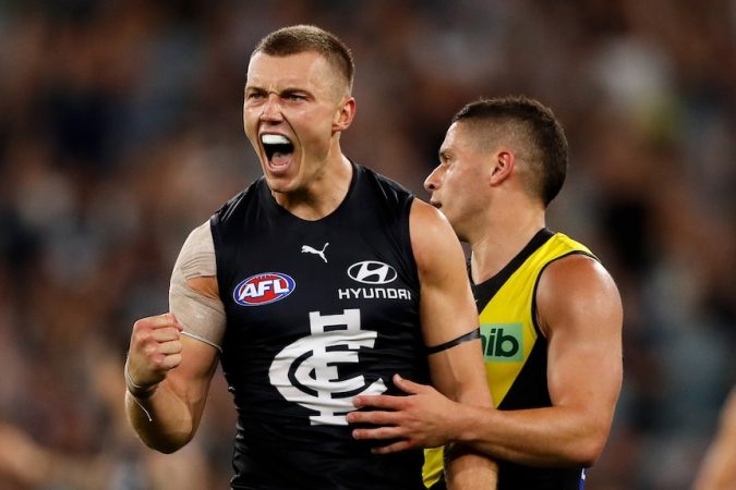 Patrick Cripps pumps his fist in celebration in the vicinity of a Richmond player