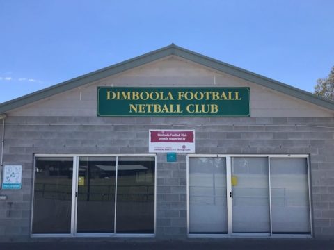 a greay brick building with a blue green sign that read dimbool football netball club