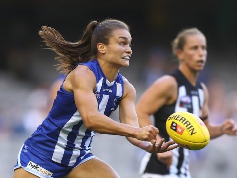 Ash Riddell grimaces as she punches a yellow AFL ball out of her hand