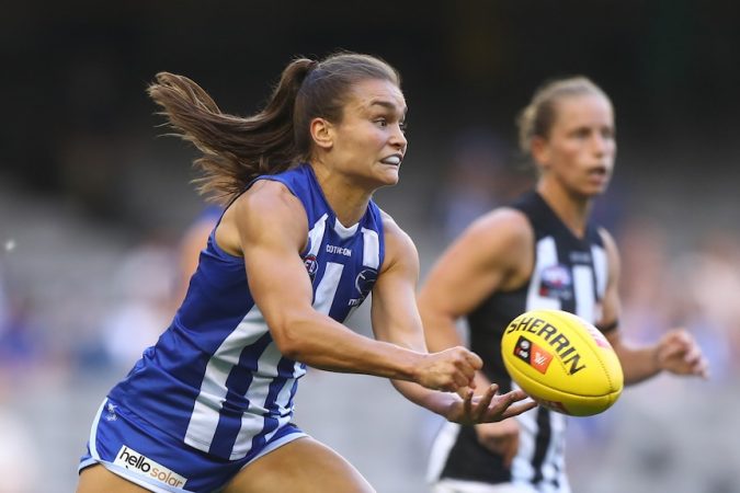 Ash Riddell grimaces as she punches a yellow AFL ball out of her hand