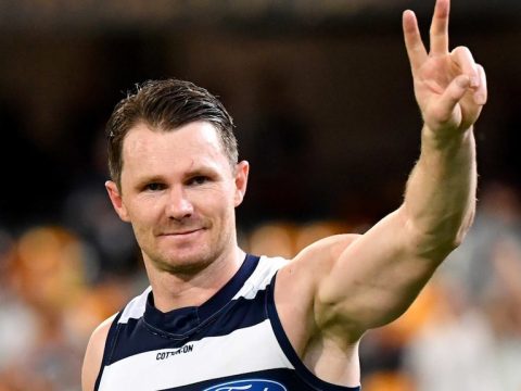 Patrick Dangerfield smiles and gives the peace sign towards the crowd