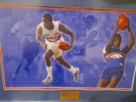 Images of an Aboriginal footballer in a Western Bulldogs guernsey, in a picture frame with a plaque underneath
