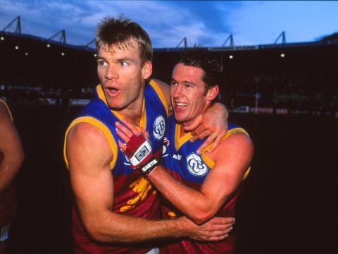 Richard Champion and Craig McRae smile with their arms around each other.