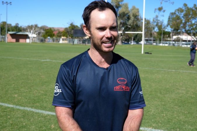 Tommy Dutton smiles while wearing a Footy 4 Life t-shirt