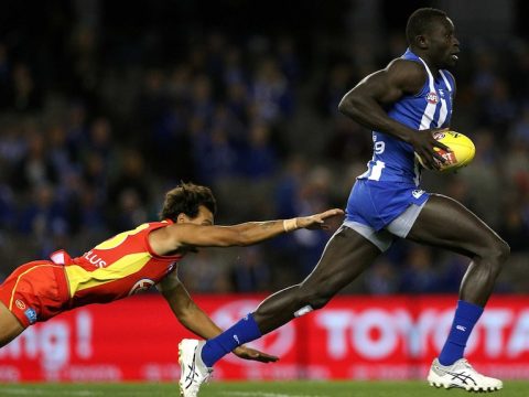 Majak Daw outruns a diving Callum Ah Chee during the round 16 AFL match between the Kangaroos and Suns.