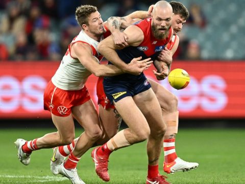 The ball spills loose as Max Gawn is tackled by two Swans players