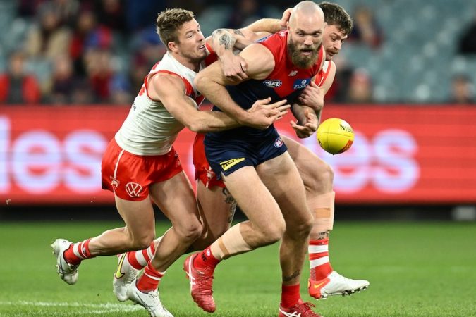 The ball spills loose as Max Gawn is tackled by two Swans players