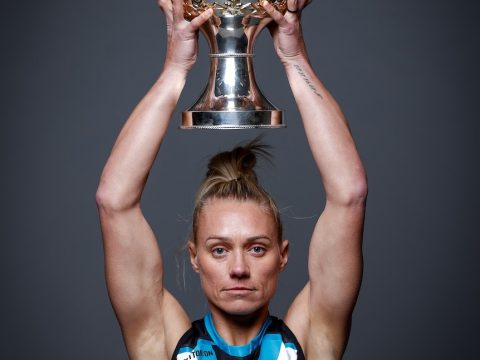 Erin Phillips poses in a Port jumper while holding the Premiership Cup on her head.