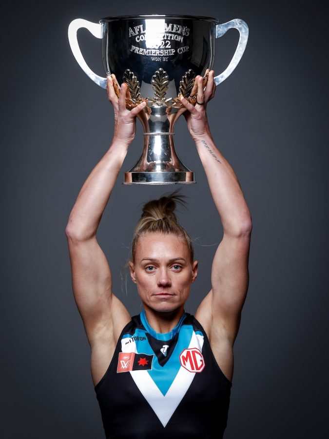 Erin Phillips poses in a Port jumper while holding the Premiership Cup on her head.
