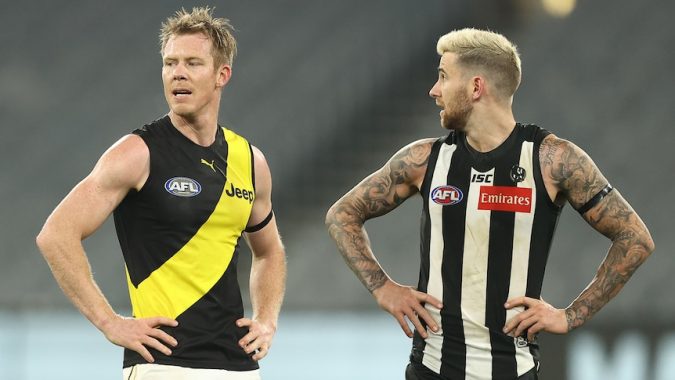 Two AFL players from Richmond and Collingwood stand side by side with hands on hips after a drawn game.