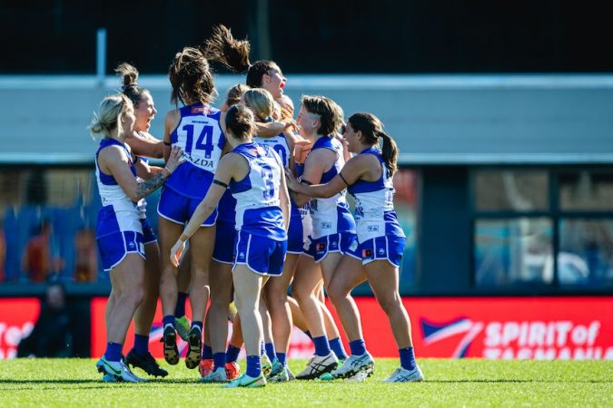 A large number of North Melbourne players gather together to celebrate a goal