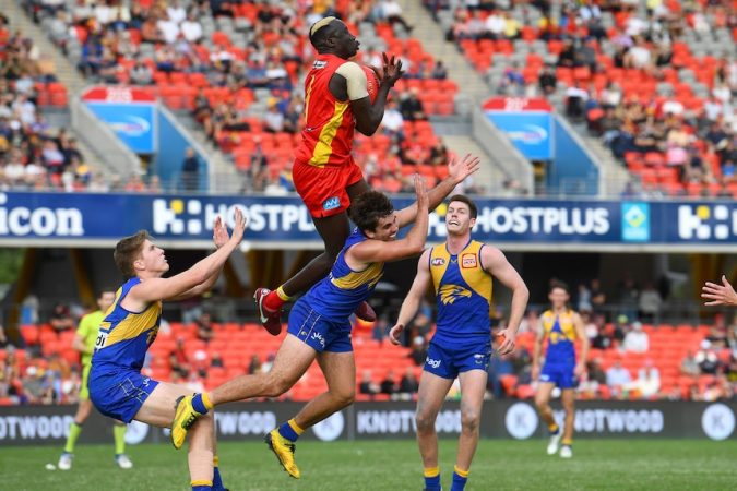 A Gold Coast AFL player takes an aerial mark over a West Coast opponent.