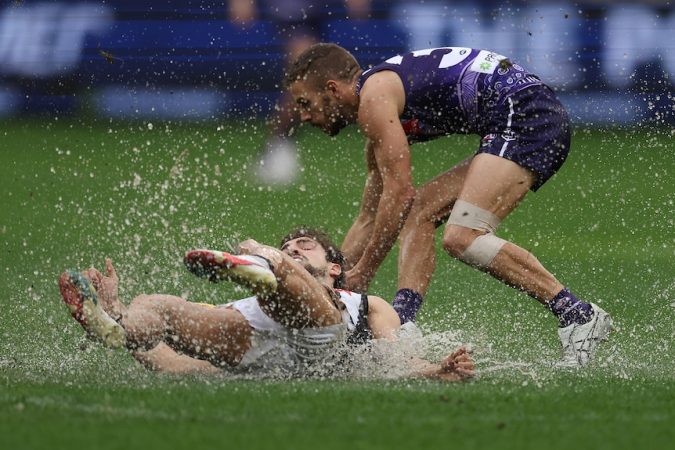 Josh Daicos and Sam Switkowski splash in a puddle