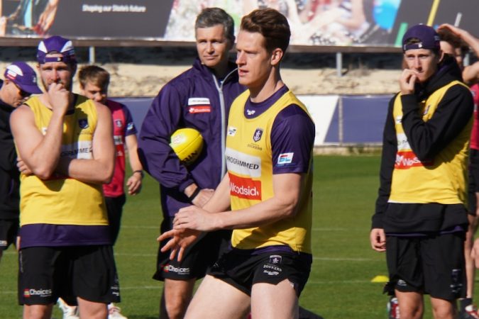 Docker coach Justin Longmuir wearing a purple tracksuit top and shorts watches Matt Taberner at a training session.