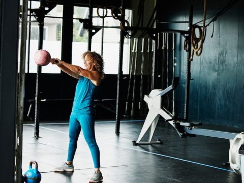 A woman doing kettlebell swings during workout in gym