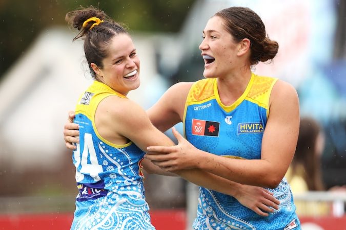 Two Gold Coast Suns AFLW players embrace as they celebrate a goal.
