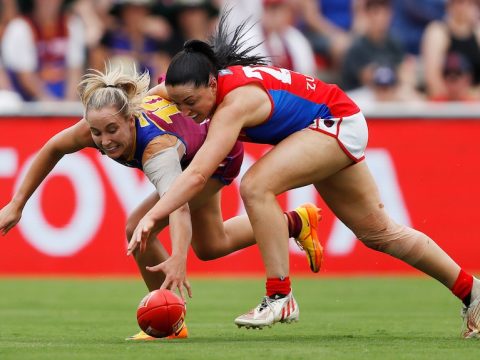 A Brisbane Lions AFLW player contests for the ball alongside a Melbourne opponent.