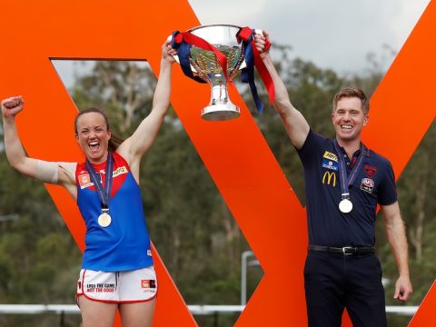 Daisy Pearce and Mark Stinear smile as they hold up the premiership cup