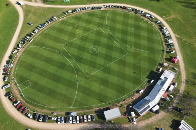An aerial view of cars parked around a football oval.