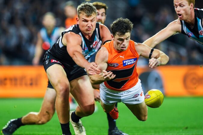 Brent Daniels of GWS dives for a ball as Port Adelaide's Ollie Wines pursues during an AFL semifinal.