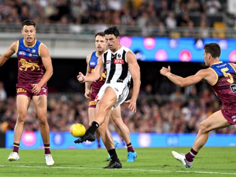 Scott Pendlebury kicks the ball as Lions opponents watch on