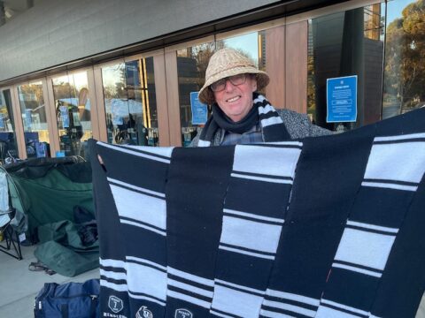 Peter Whitfield holds up fabric in Collingwood colours.