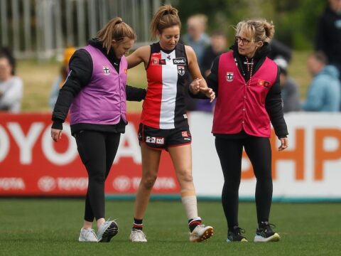 A St Kilda AFLW player is helped from the field after sustaining a knee injury.