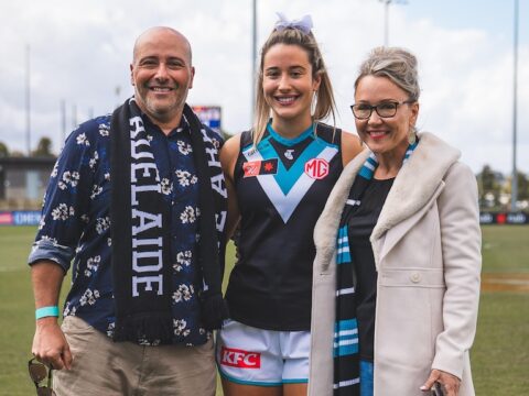 Amelie Borg is pictured with her parents at Alberton Oval in Port Adelaide gear